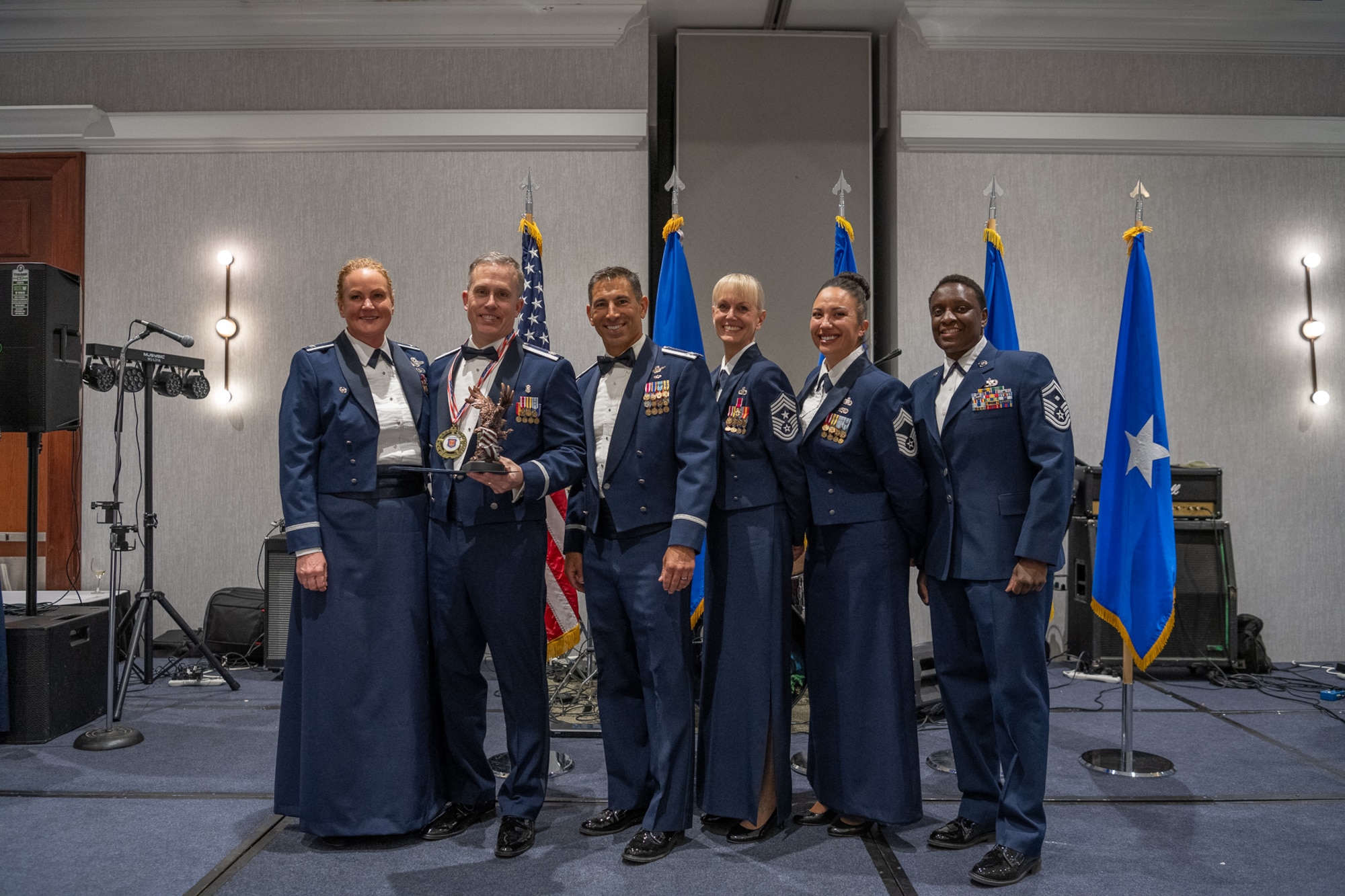 A row of servicemembers stand on stage together.