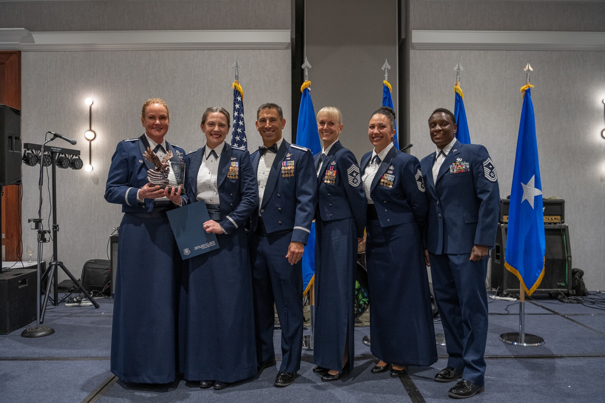 A row of servicemembers stand together on stage.