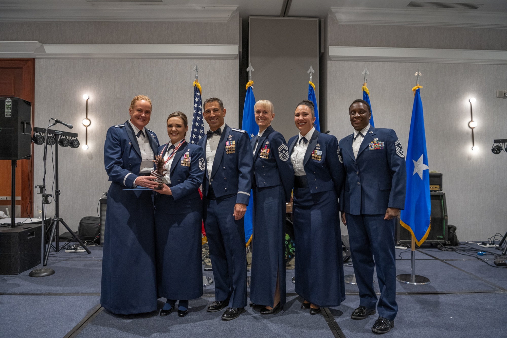 A row of servicemembers stand together on stage.
