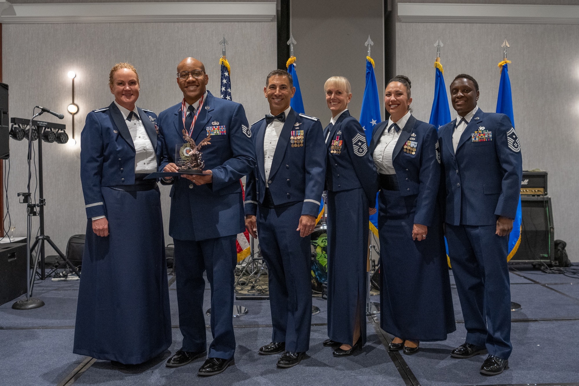 A row of servicemembers stand together on stage.