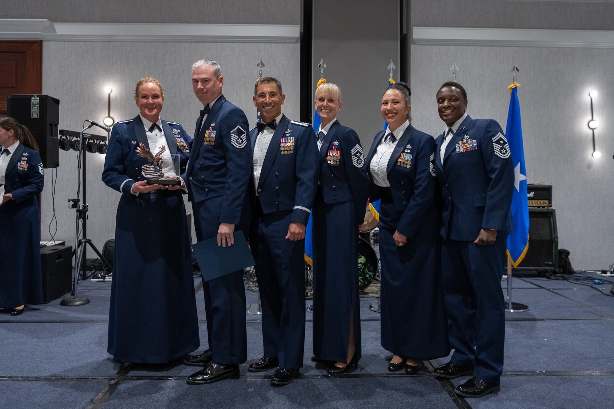 A row of servicemembers stand together on stage.