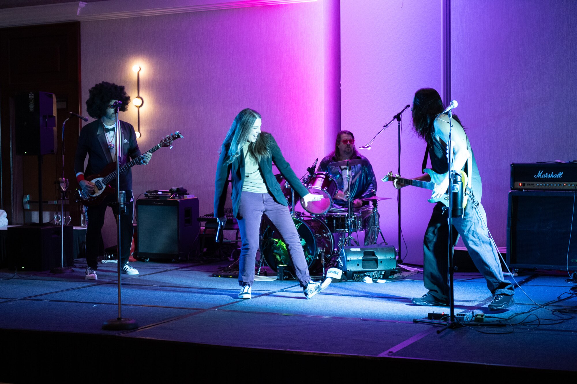 A band playing on stage with colorful lighting.