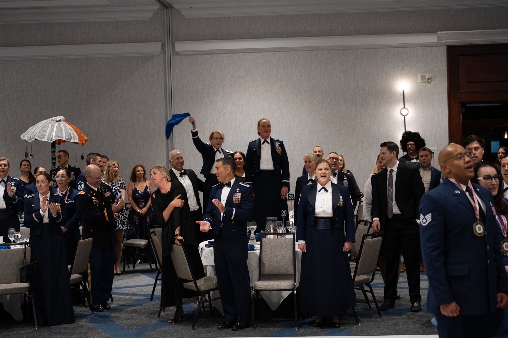 A group of servicemembers cheering in a ballroom.