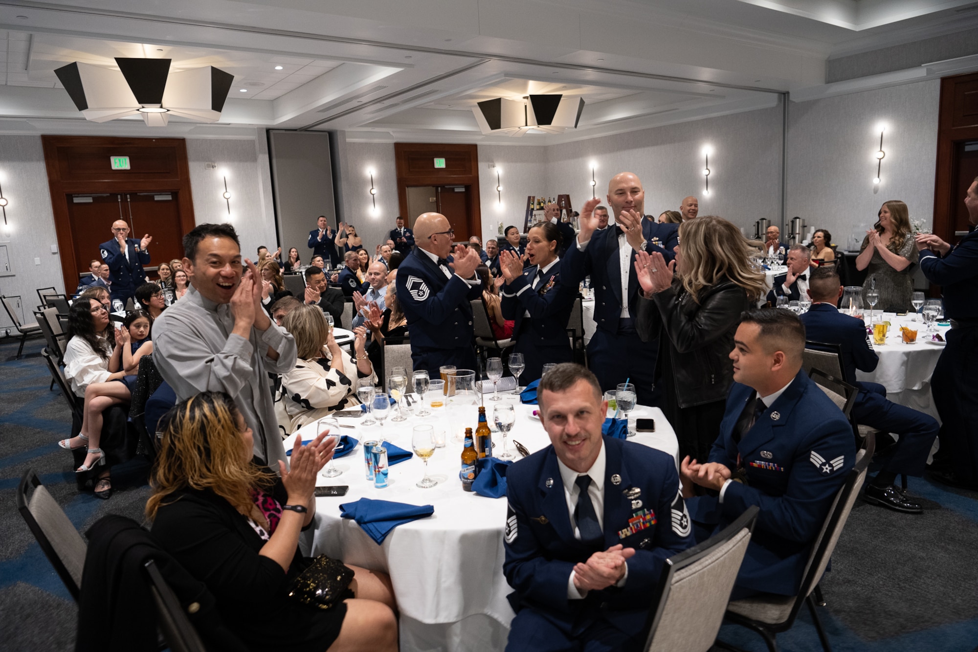 A group of servicemembers cheering in a ballroom.