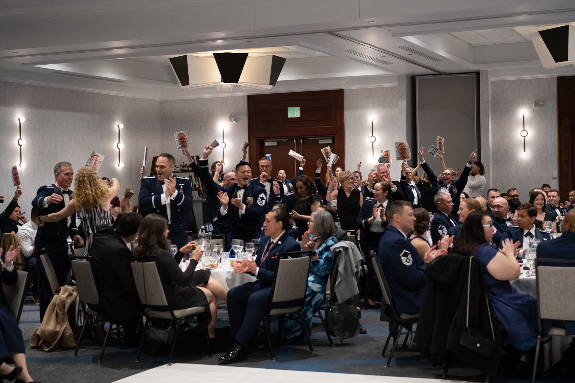A group of servicemembers cheering in a ballroom.