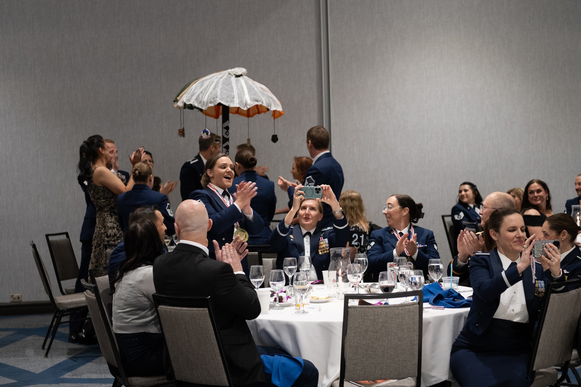 A group of servicemembers cheering in a ballroom.