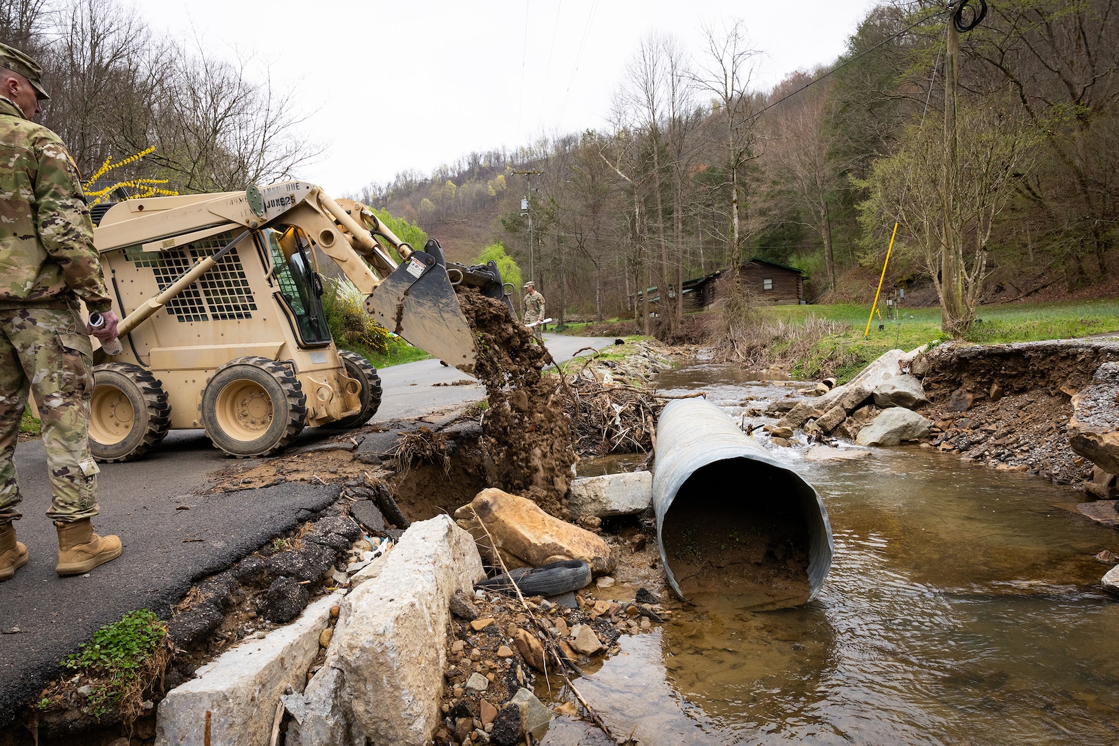 U.S. Army Sgt. Brian Mccall uses a skid steer to repair roadsides on a county road in Hindman, Ky. on April 1, 2025.