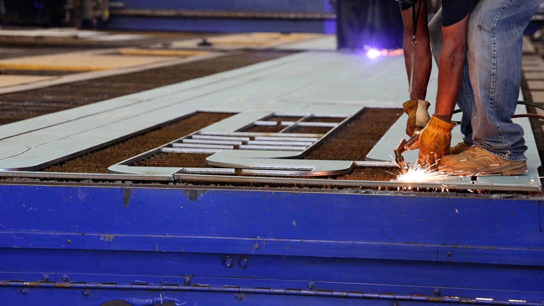 The U.S. Army Corps of Engineers joined contractors Eastern Shipbuilding Group and Royal IHC on April 4, 2025, in Panama City, FL for a steel cutting ceremony, kicking off construction of a Medium Class Hopper Dredge to replace the Dredge McFARLAND of the Army Corps’ Philadelphia. The first cuts were made by a CNC Plasma Arc Burning Machine on an 8’ x 50’ x 5/8” sheet of ABS-14 raw steel plate from which templated pieces were then punched out individually.