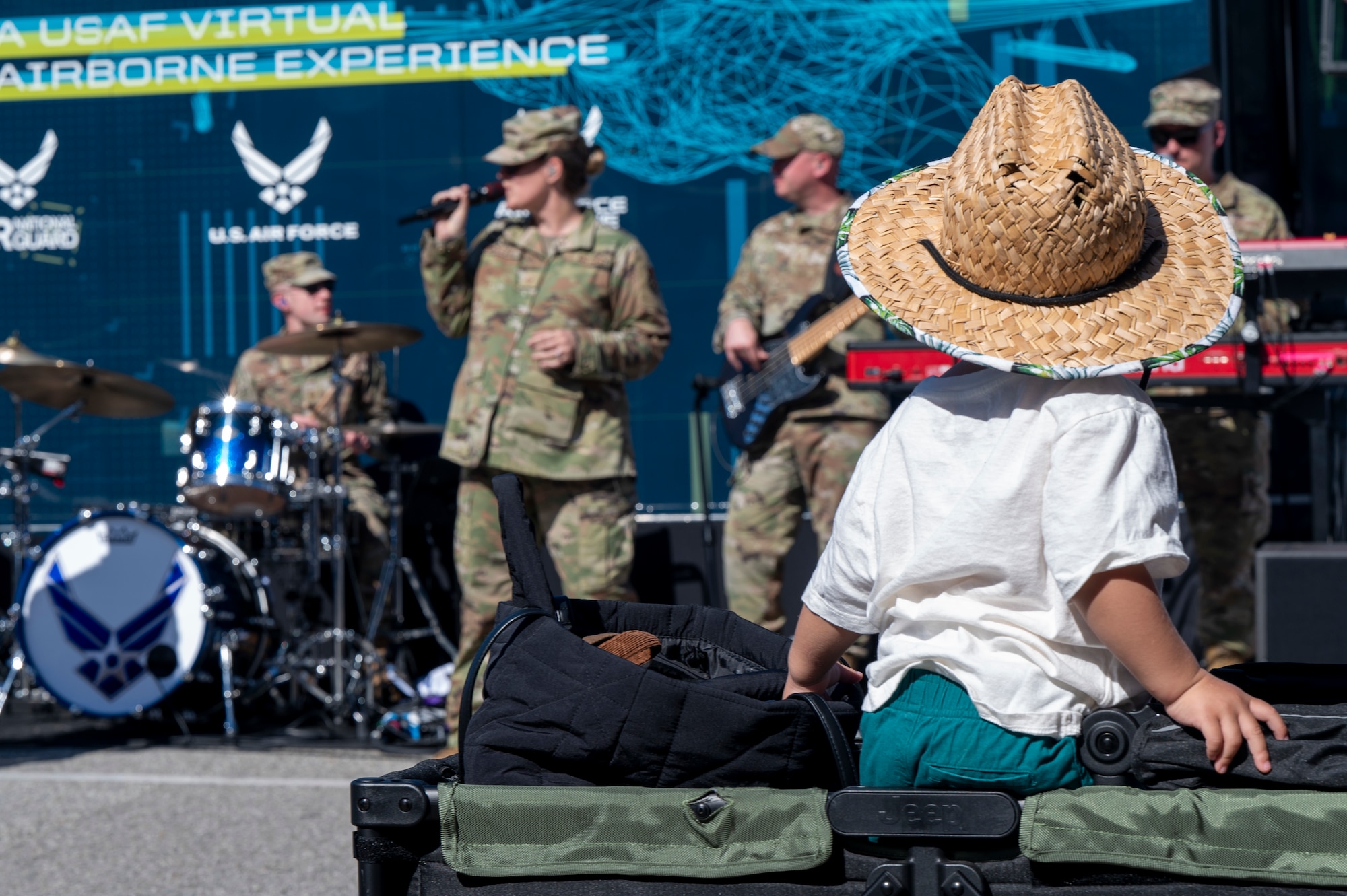 A child watches members of The U.S. Air Force Band’s Max Impact perform during the Southern California tour at a Formula Drift event, Long Beach, Calif., April 5, 2025. The mission of Max Impact, a rock band, is to honor those who have served, inspire American citizens to heightened patriotism and service, and connect the global community on behalf of the Air Force and the United States. Max Impact consists of six active-duty musicians stationed at Joint Base Anacostia-Bolling, Washington, D.C. (U.S. Air Force photo by Hayden Hallman)