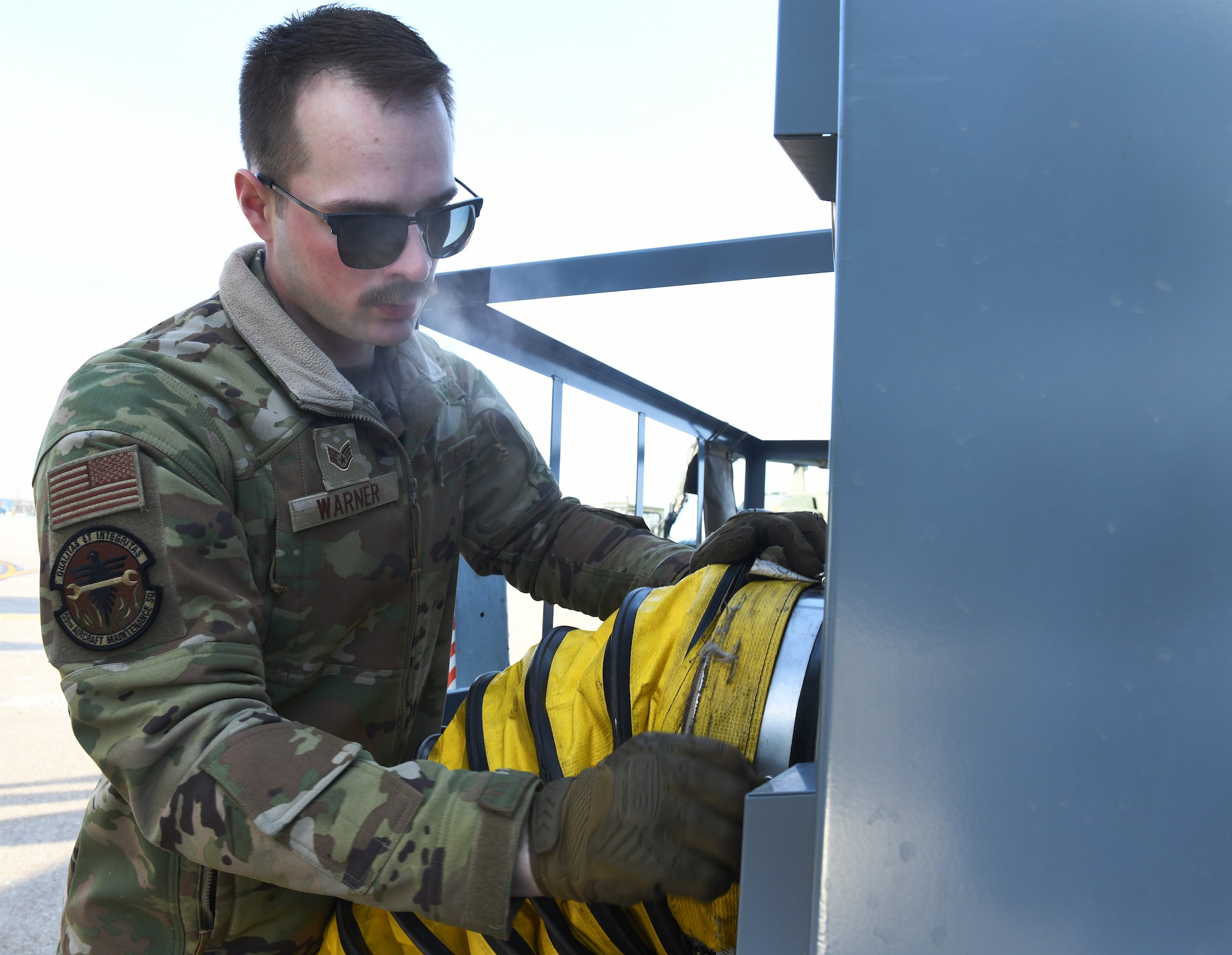 Airman connects external belly air hose to 808 air conditioning cart.
