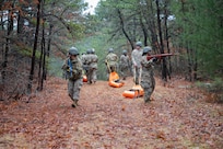 Airmen drag mannequins through the woods.