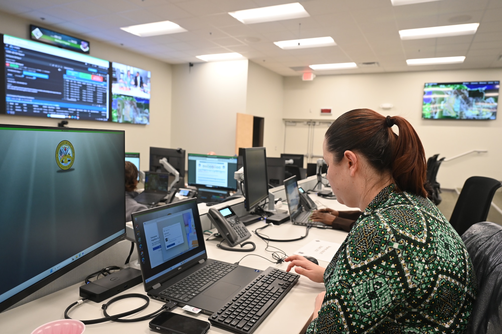 Woman sits in a room of screen and turns on her screen to login and an provide a demonstration.