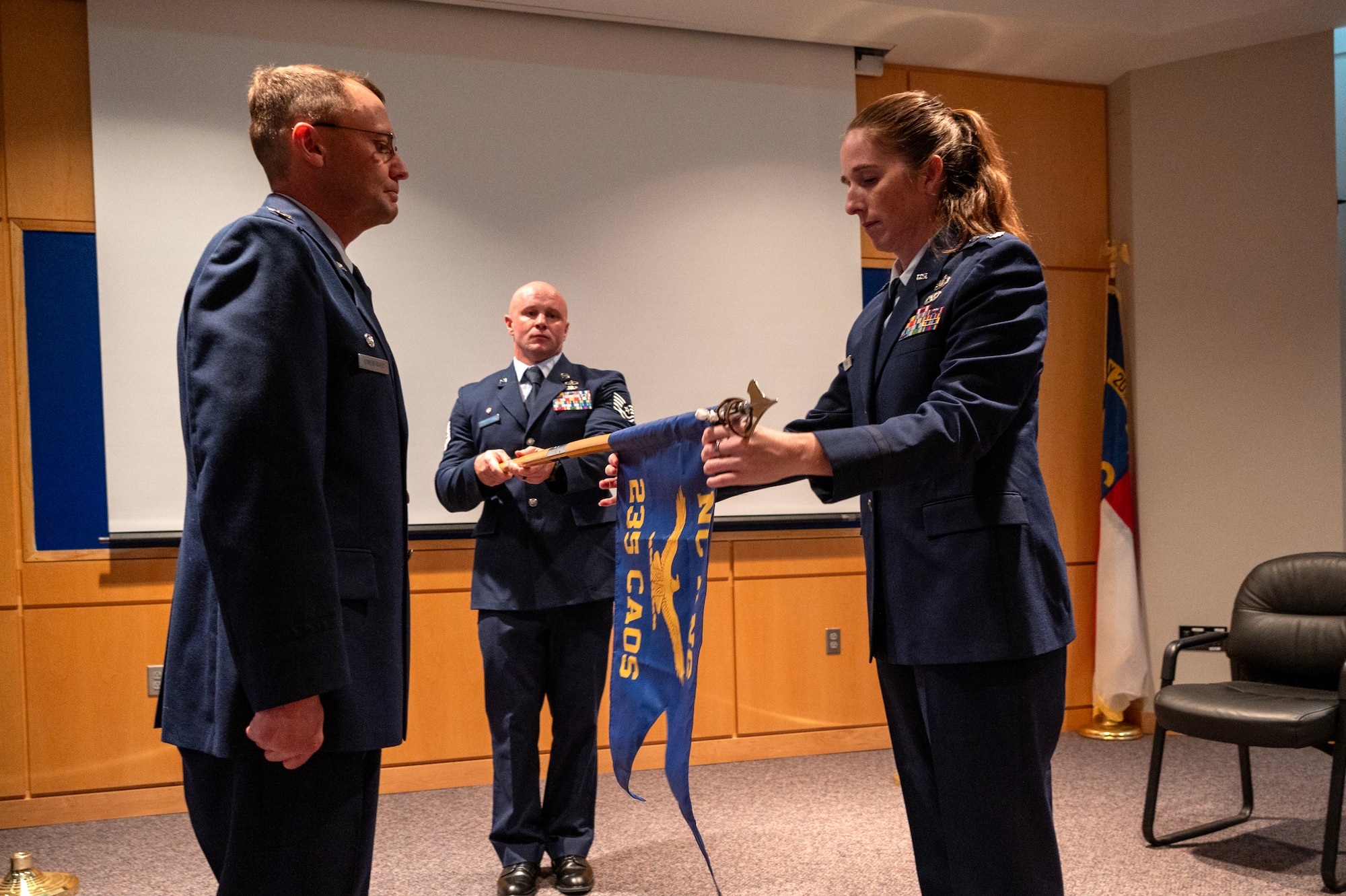 U.S. Air Force Col Michael S. Lineberger, 145th Operations Group commander, left, and Lt. Col. Erin M. Root, 235th Combat Airfield Operations Squadron (235 CAOS) commander, right, unveil the 235 CAOS flag at a redesignation ceremony at the North Carolina Air National Guard’s New London, N.C. location, March 7, 2025.