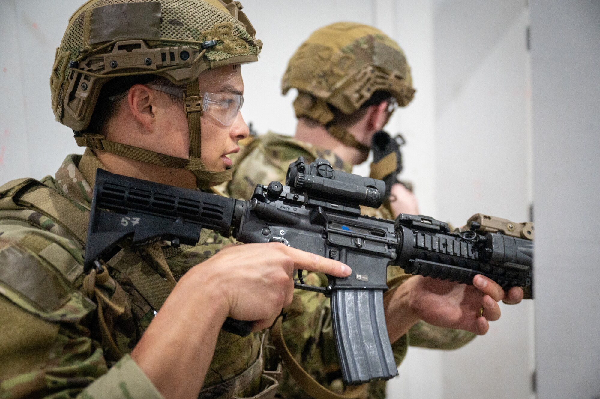 a man holds a fake gun as he looks around a corner offscreen