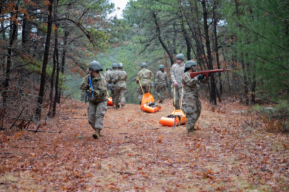 Airmen drag mannequins through the woods.