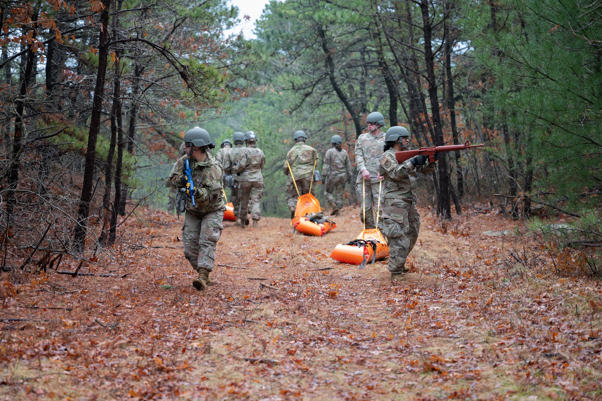 Airmen drag mannequins through the woods.