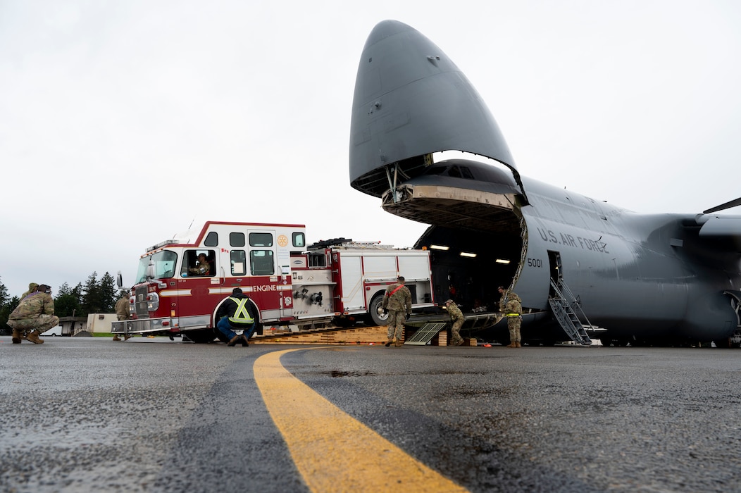 U.S. Air Force Airmen with the 62d Aerial Port Squadron, 446th APS and 709th Airlift Squadron from Dover Air Force Base, Delaware, load a fire truck onto a C-5M Super Galaxy at Joint Base Lewis-McChord, Washington, April 8, 2025. 
A donated fire truck arrived at JBLM via flatbed truck to be shipped to Guatemala in support of the Denton Humanitarian Assistance Program.