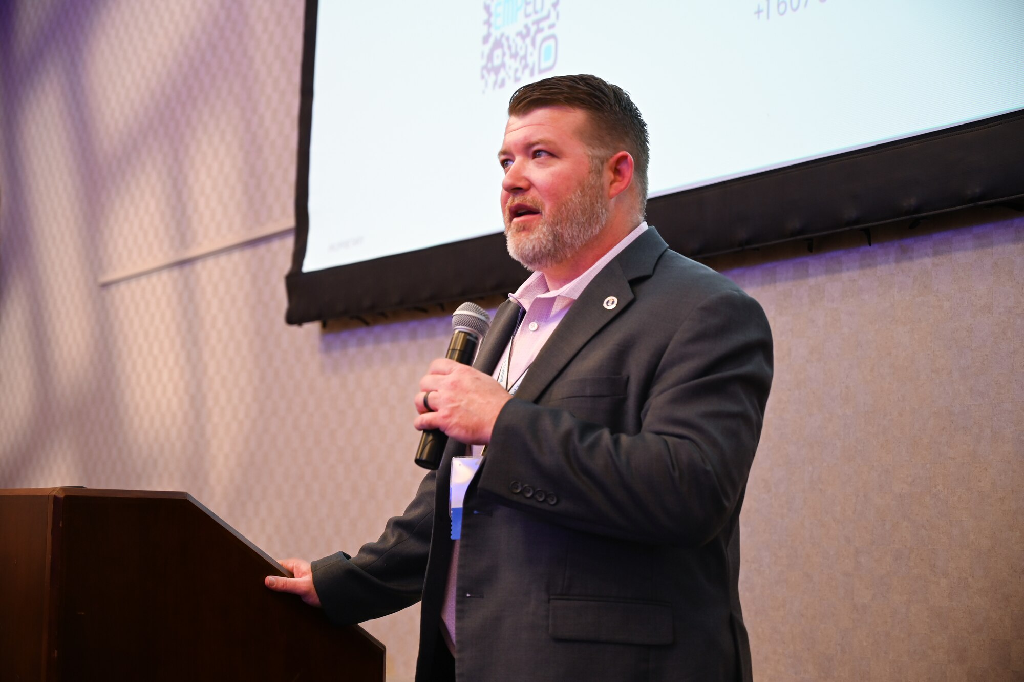 A man stands at a podium, holding a microphone