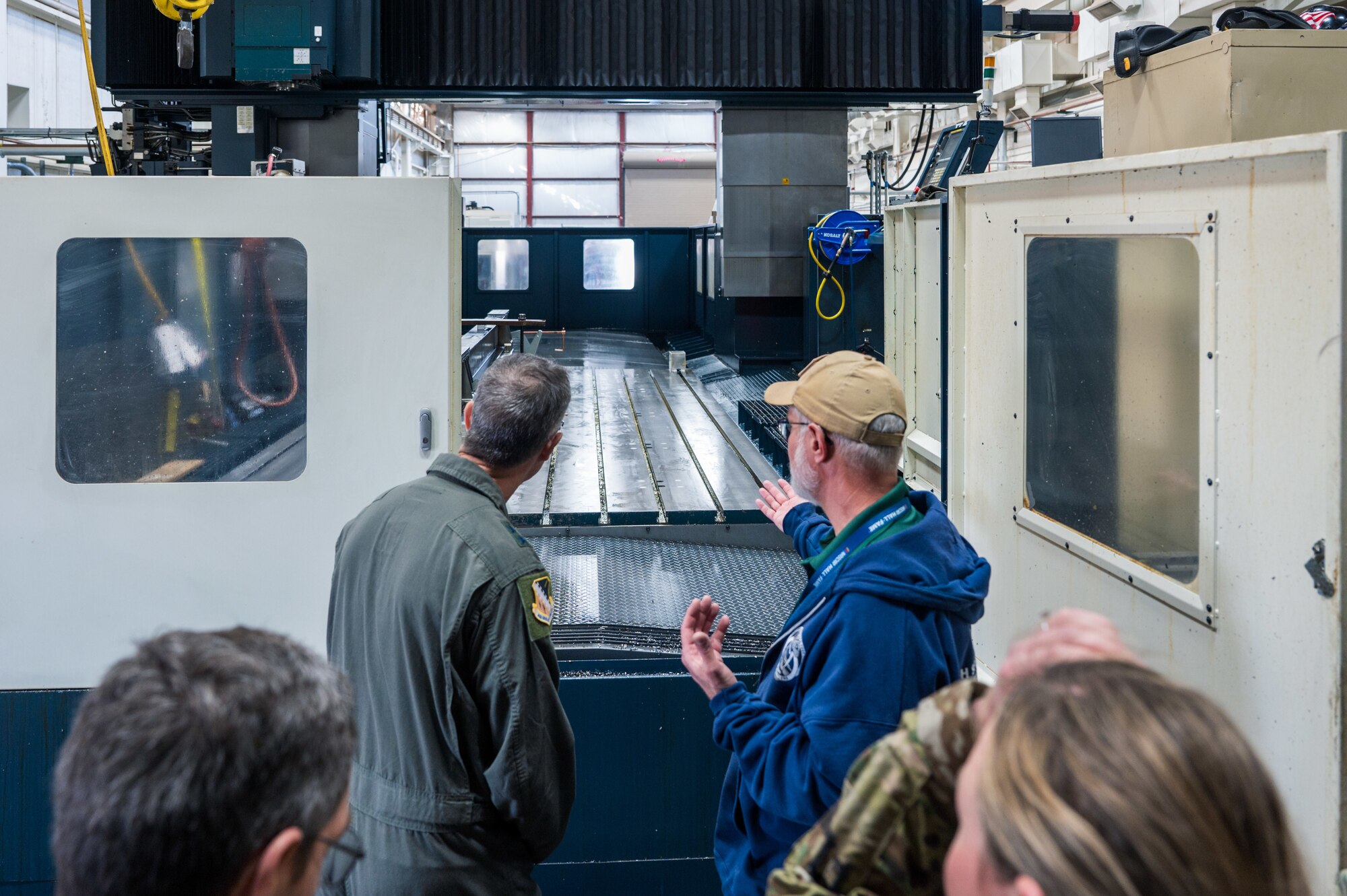 U.S. Air Force Maj. Gen. Scott Cain, Air Force Test Center commander, left, hears about machining processes from Ziggy Pieszala, 846th Test Squadron model maker supervisor, at Holloman Air Force Base, New Mexico, March 21, 2025. Pieszala discussed various equipment used in daily work and suggestions for upgrades. (U.S. Air Force photo by Airman 1st Class Bob Teichmann)