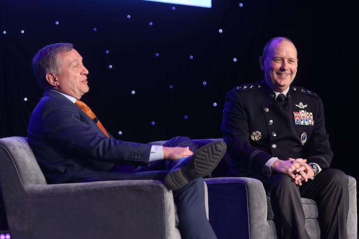 Two men sit in chairs next to eachother for interview