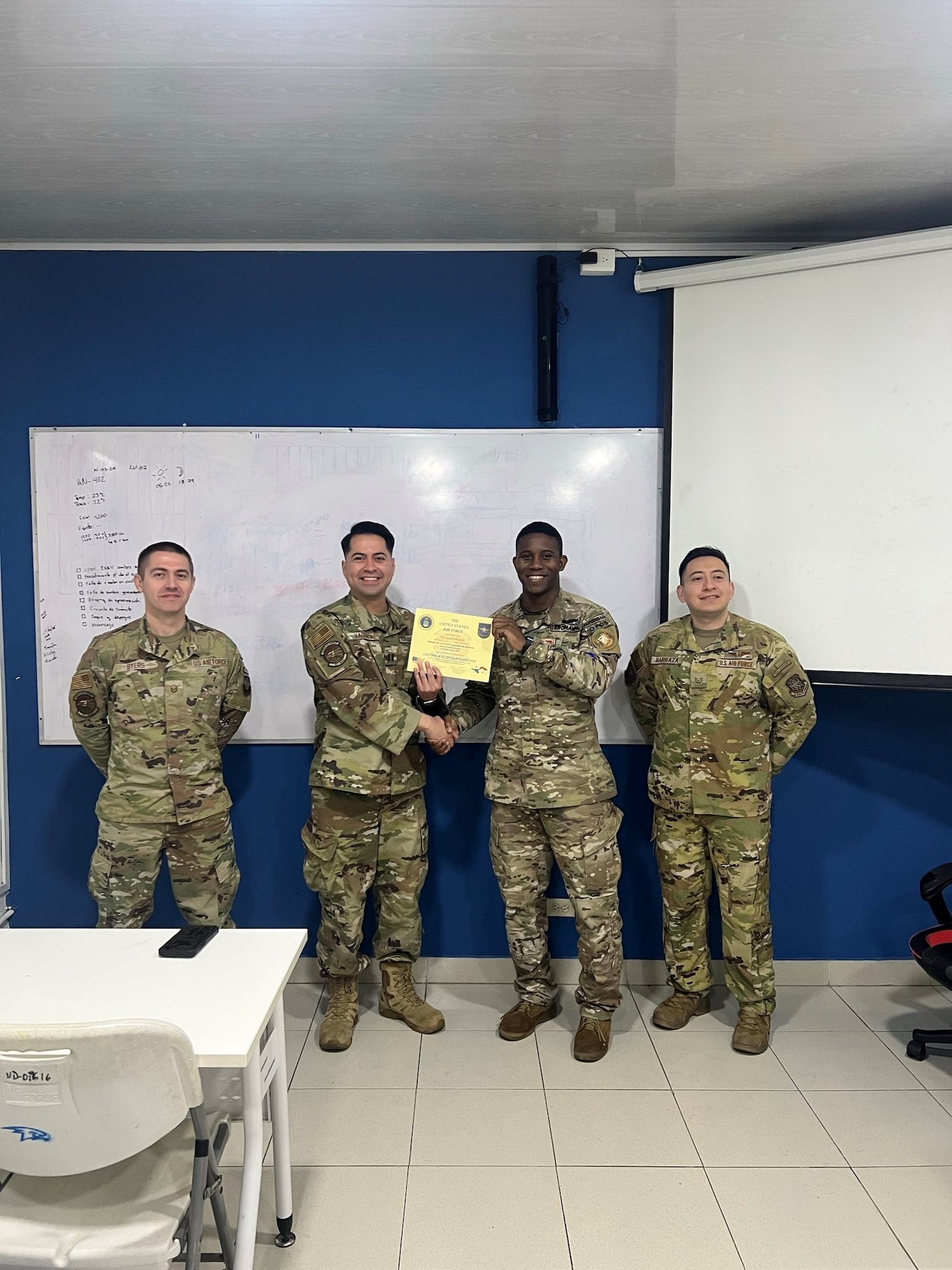 Men pose for a photo holding a certificate.
