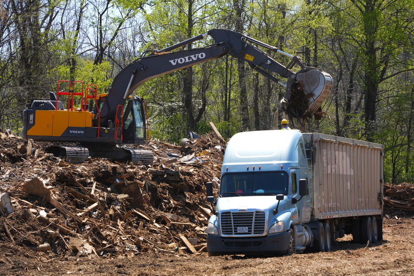 An excavator loads construction and demolition debris into a tractor-trailer at the Old Fort Debris Management Site in Old Fort, North Carolina, April 9, 2025. The site supports Hurricane Helene recovery by facilitating the proper sorting and removal of storm-related debris