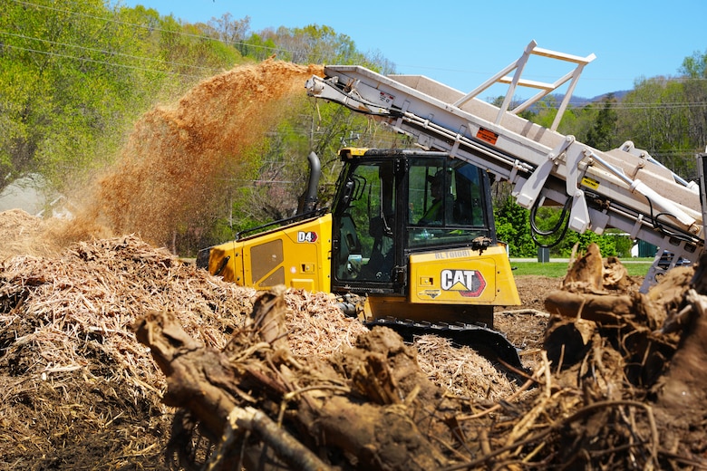 A bulldozer stands ready to move mulch into place as ground debris exits the grinder's conveyor system at the Old Fort Debris Management Site in Old Fort, North Carolina, April 9, 2025. The debris was collected from waterways and rights-of-way impacted by Hurricane Helene.