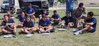 students sitting on ground with rope in front of them
