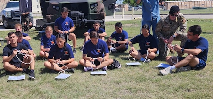 students sitting on ground with rope in front of them