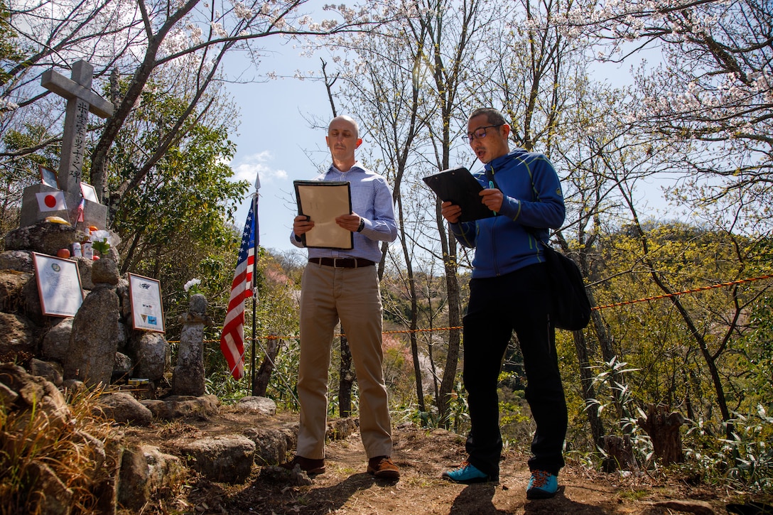 U.S. Marine Corps Maj. Matthew Forshee, left, the executive officer of Headquarters and Headquarters Squadron, Marine Corps Air Station Iwakuni and a native of Texas, reads a message from the Commander of U.S. Naval Forces Japan while Takayuki Takeda, a master labor contractor with Headquarters and Headquarters Squadron, MCAS Iwakuni, translates it to the members of the Meitoku District Association during the 80th anniversary of the Marukoyama Memorial Ceremony in Kure City, Hiroshima Prefecture, Japan, April. 3, 2025. The Marukoyama Memorial Ceremony is held every year in Kure during cherry blossom season to honor the crew members of the U.S. Navy TBM-3 Avenger, Torpedo Squadron 6, who died in Kure City, Hiroshima Prefecture, Japan, on July 24, 1945. (U.S. Marine Corps photo by Sgt. Randall Whiteman)