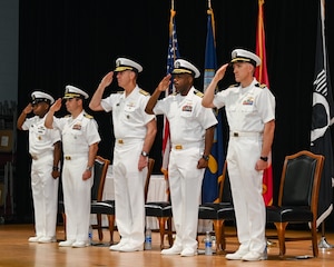 U.S. Navy Capt. Tim Campbell, center left, outgoing commander of Task Force (CTF) 57, U.S. Navy Vice Adm. George Wikoff, center, commander of U.S. Naval Forces Central Command and U.S. 5th Fleet, and U.S. Navy Capt. Dennis Jensen, center right, incoming commander of CTF 57, render honors during a change-of-command ceremony in Manama, Bahrain