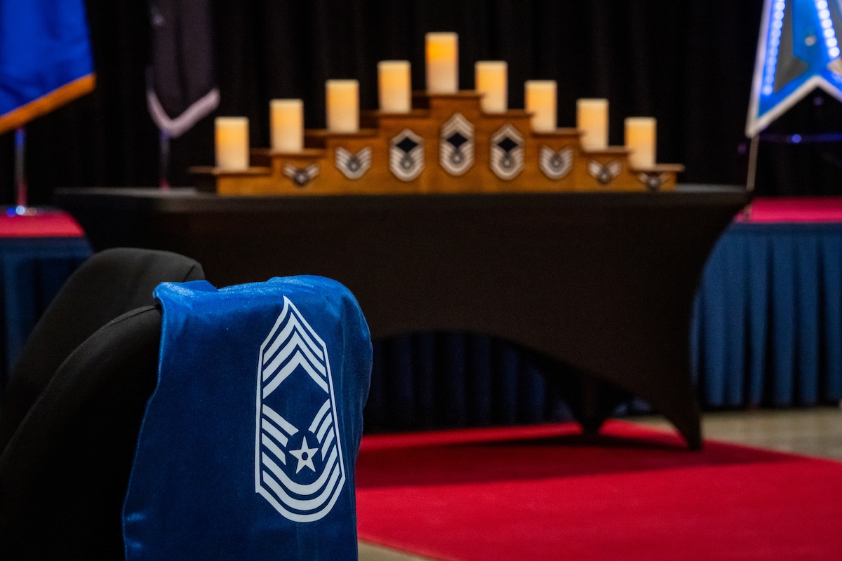A tiered candle holder with military ranks is displayed in the background with a chief master sgt. rank draped over a chair in the foreground