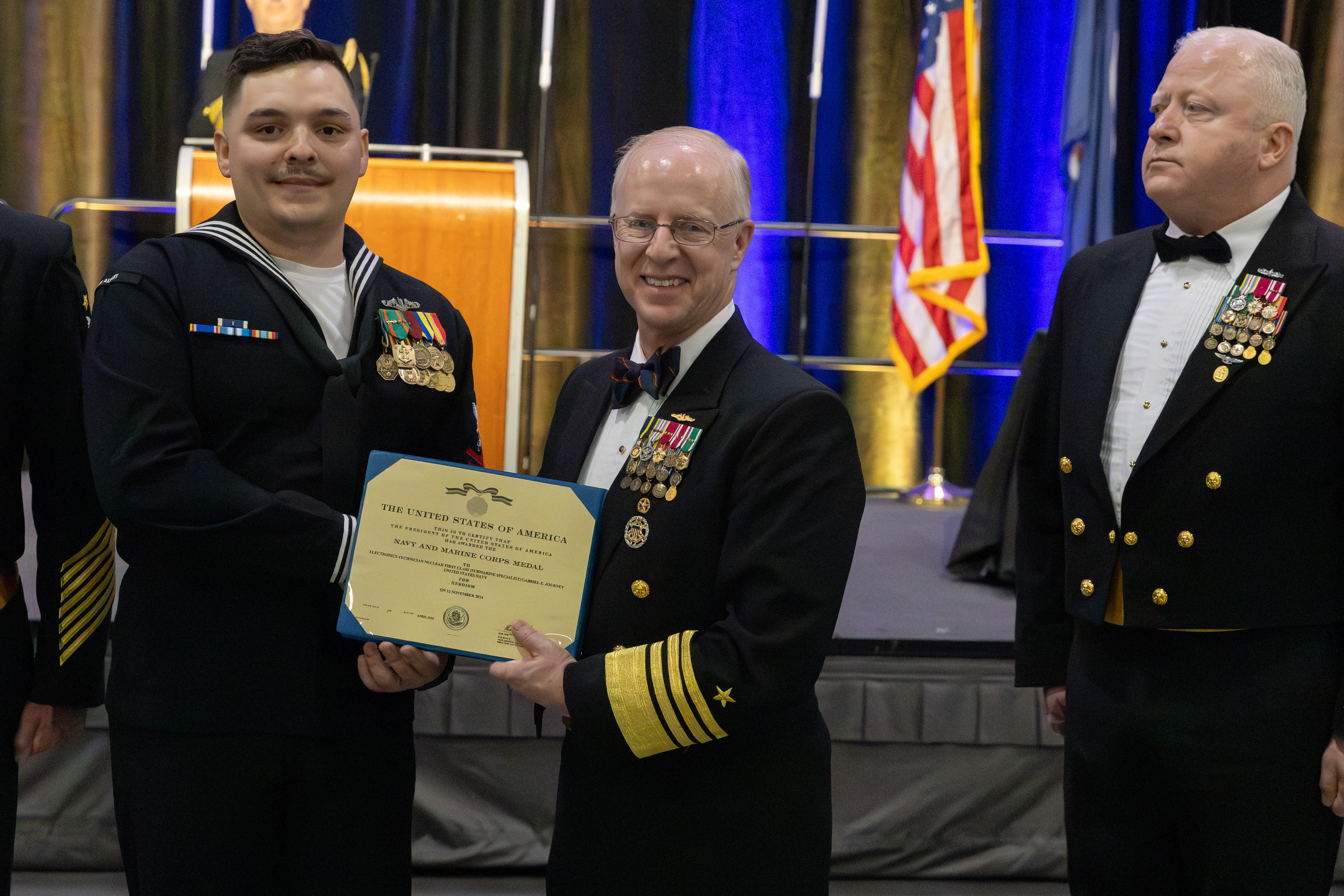 Adm. Caudle presents the Navy and Marine Corps Medal to ETN1 Journey