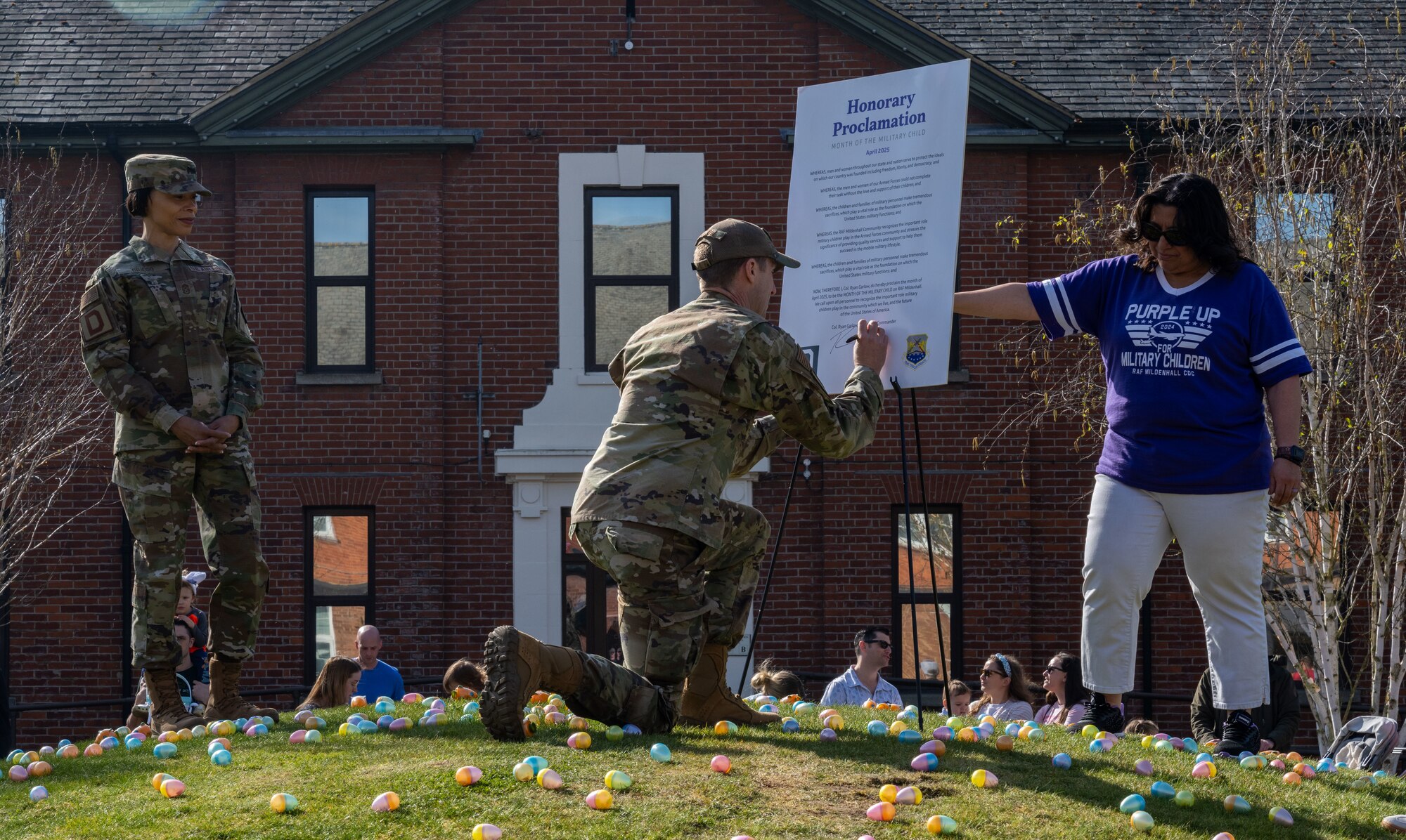 U.S. Air Force Col. Ryan Garlow, 100th Air Refueling Wing commander, signs the Month of the Military Child proclamation during the Eggstravaganza event at RAF Mildenhall, England, April 12, 2025.