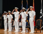 U.S. Navy Capt. Tim Campbell, center left, outgoing commander of Task Force (CTF) 57, U.S. Navy Vice Adm. George Wikoff, center, commander of U.S. Naval Forces Central Command and U.S. 5th Fleet, and U.S. Navy Capt. Dennis Jensen, center right, incoming commander of CTF 57, render honors during a change-of-command ceremony in Manama, Bahrain