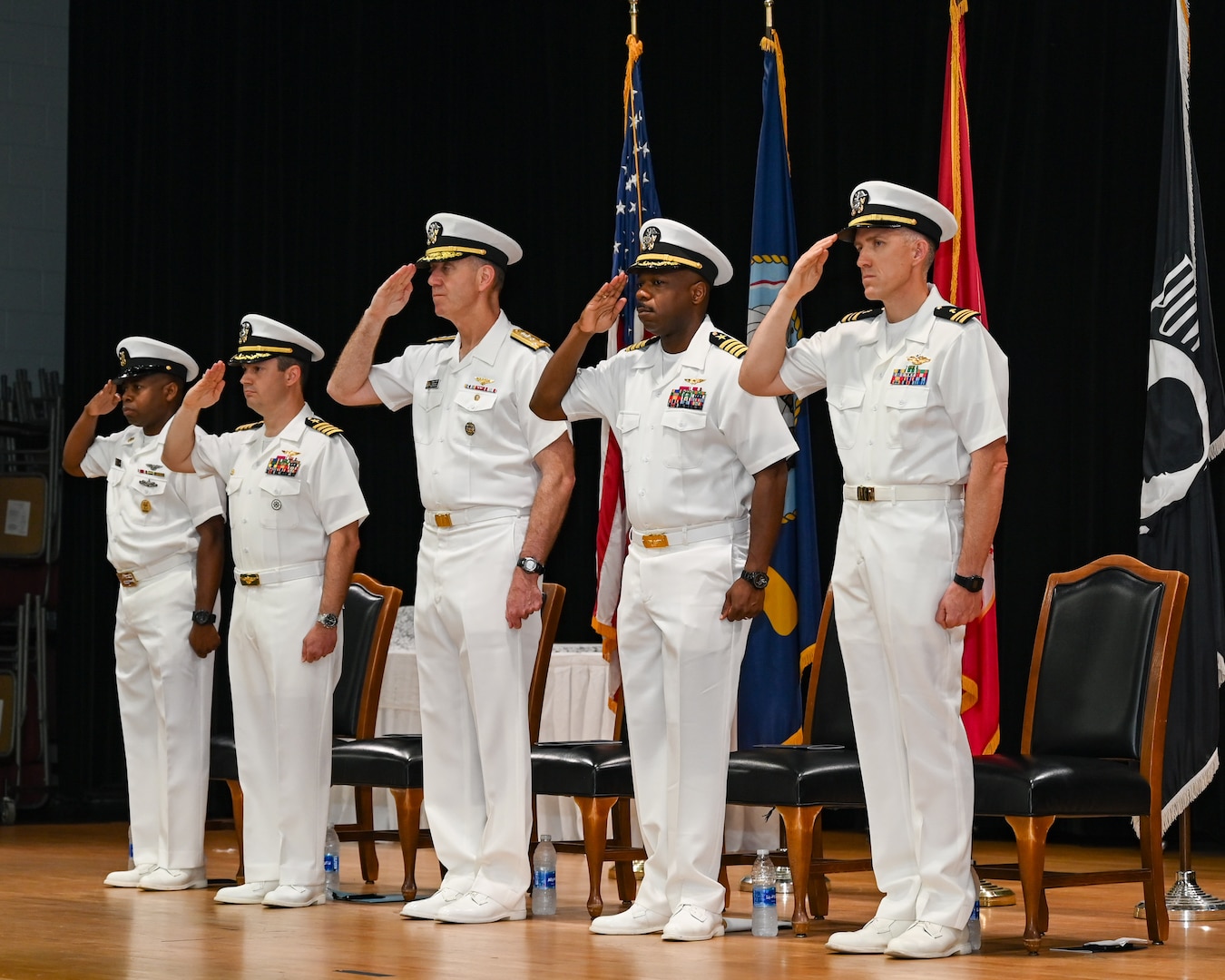 U.S. Navy Capt. Tim Campbell, center left, outgoing commander of Task Force (CTF) 57, U.S. Navy Vice Adm. George Wikoff, center, commander of U.S. Naval Forces Central Command and U.S. 5th Fleet, and U.S. Navy Capt. Dennis Jensen, center right, incoming commander of CTF 57, render honors during a change-of-command ceremony in Manama, Bahrain