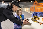John Paul Kunewa, platform general foreman, Code 760, Dive Locker, shows a student how to use an electric machine arm April 19, 2025, during “Navy STEM Days” at the U.S. Naval Undersea Museum, in Keyport, Washington. (U.S. Navy photo by Jeb Fach)