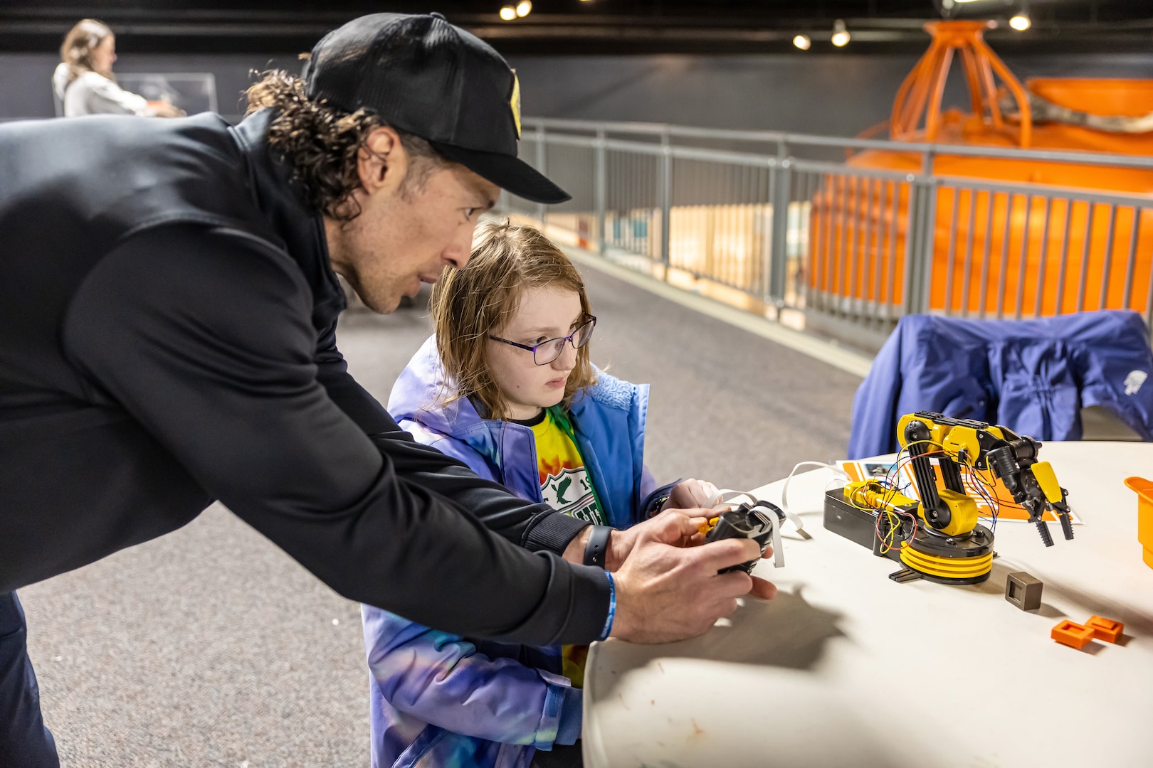 John Paul Kunewa, platform general foreman, Code 760, Dive Locker, shows a student how to use an electric machine arm April 19, 2025, during “Navy STEM Days” at the U.S. Naval Undersea Museum, in Keyport, Washington. (U.S. Navy photo by Jeb Fach)