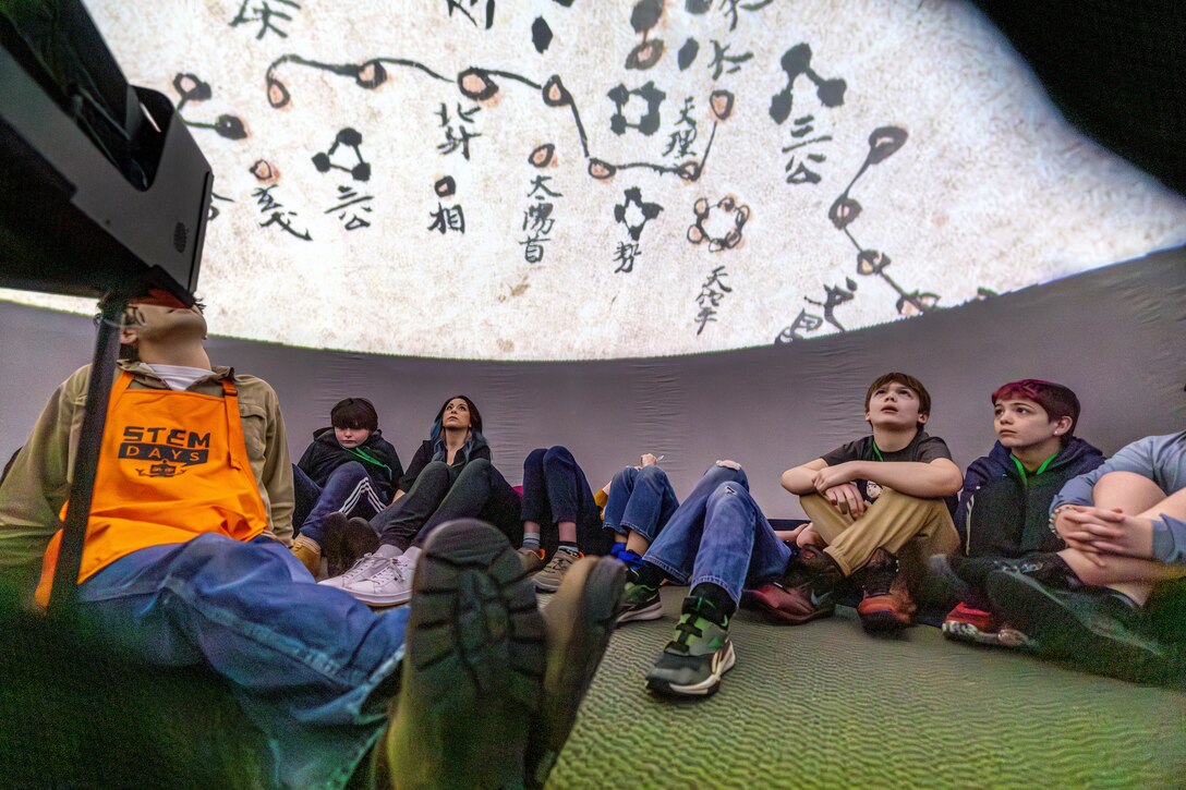Ethan Austin, STEM outreach volunteer, watches a video with middle school students inside an inflatable planetarium, April 19, 2025, during “Navy STEM Days” at the U.S. Undersea Museum at Naval Undersea Warfare Center, Keyport, Washington. (U.S. Navy photo by Jeb Fach)