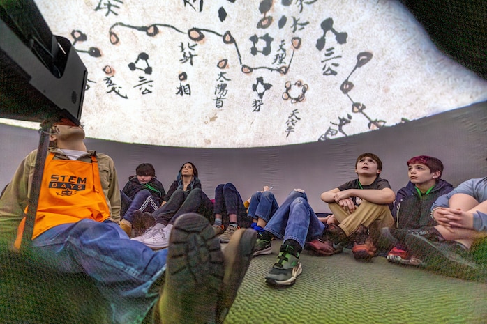 Ethan Austin, STEM outreach volunteer, watches a video with middle school students inside an inflatable planetarium, April 19, 2025, during “Navy STEM Days” at the U.S. Undersea Museum at Naval Undersea Warfare Center, Keyport, Washington. (U.S. Navy photo by Jeb Fach)