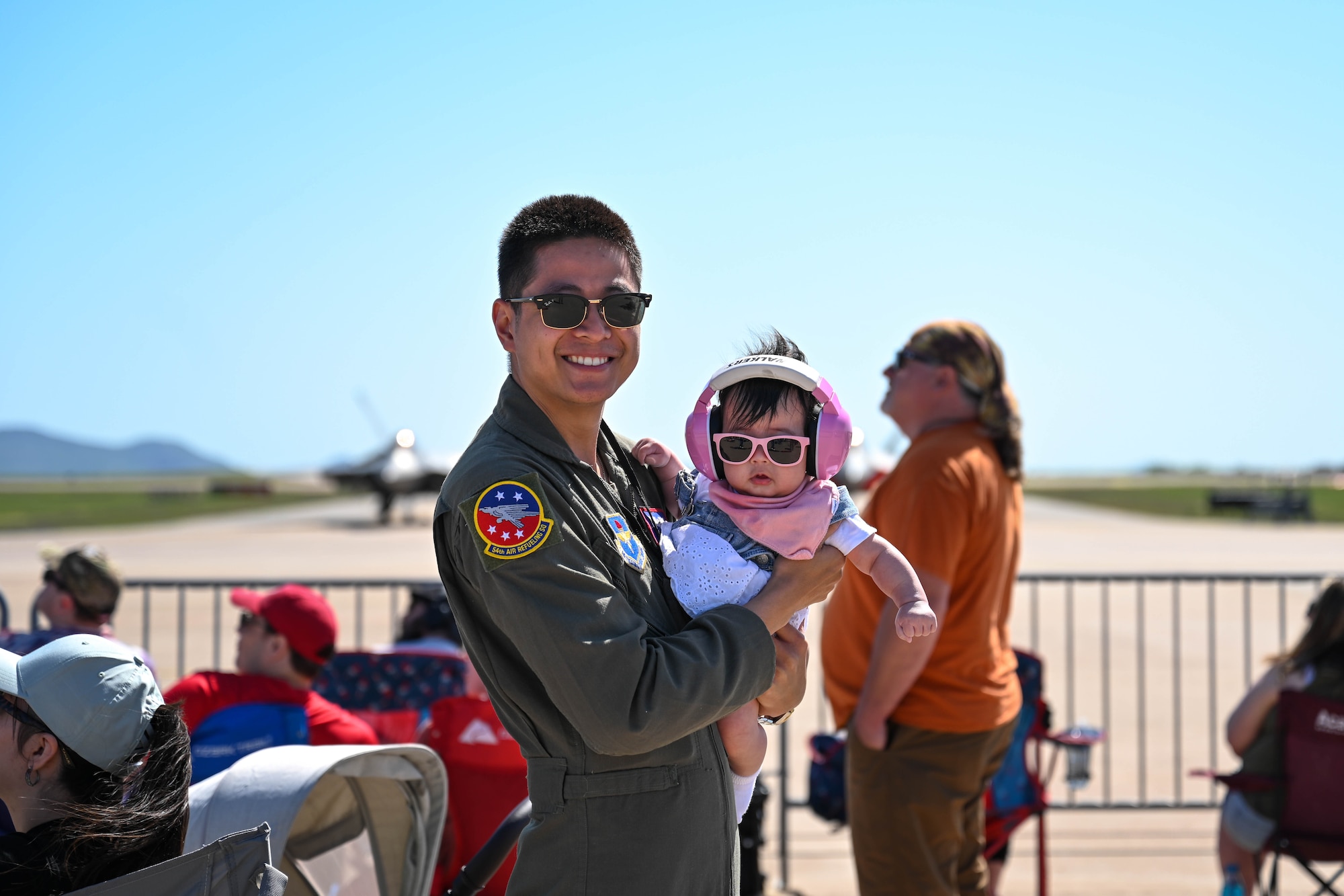 U.S. Air Force Staff Sgt. Dylan Vu, 54th Air Refueling Squadron instructor boom operator, poses for a photo with his daughter at the Altus Airpower Stampede Open House and Air Show, at Altus Air Force Base, Oklahoma, April 12, 2025. The show offered lots of entertainment, including acts from top performers such as the F-22 Raptor, F-35A Lightning II, and Tora! Tora! Tora!, a live reenactment of the Japanese bombing of Pearl Harbor. (U.S. Air Force photo by Airman 1st Class Lauren Torres)