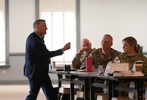 Caucasian speaker lecturing a room of senior noncommissioned officers.
