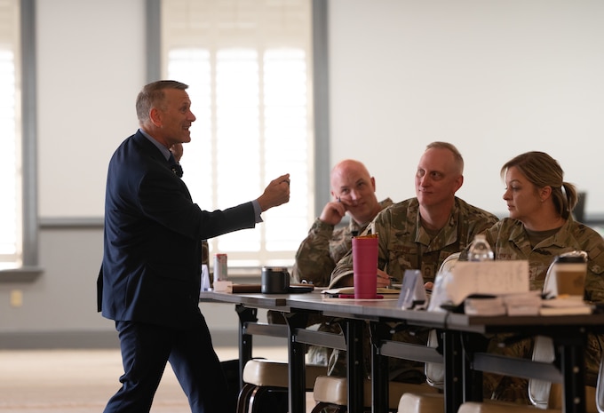 Caucasian speaker lecturing a room of senior noncommissioned officers.
