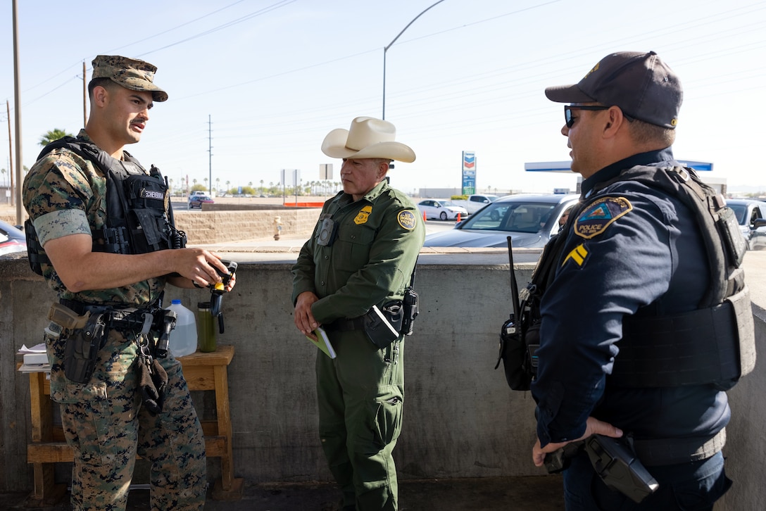 A Marine and U.S. Border Patrol agent speak to each other.