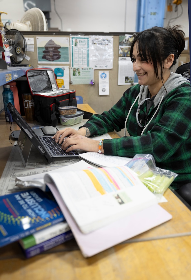 Alexandra Kopecky, refrigerator technician, Shop 06, Tooling and Maintenance, does homework for school during her lunch break, April 3, 2025, at Puget Sound Naval Shipyard & Intermediate Maintenance Facility in Bremerton, Washington.. Kopecky attends Olympic College through the school's After-Hours Program. (U.S. Navy photo by Wendy Hallmark)
