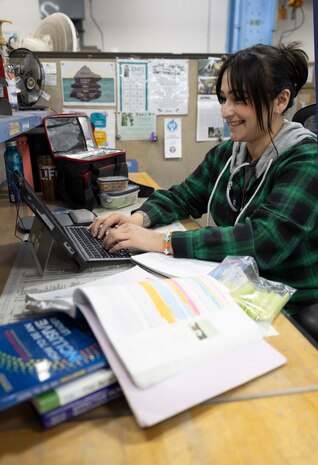 Alexandra Kopecky, refrigerator technician, Shop 06, Tooling and Maintenance, does homework for school during her lunch break, April 3, 2025, at Puget Sound Naval Shipyard & Intermediate Maintenance Facility in Bremerton, Washington.. Kopecky attends Olympic College through the school's After-Hours Program. (U.S. Navy photo by Wendy Hallmark)