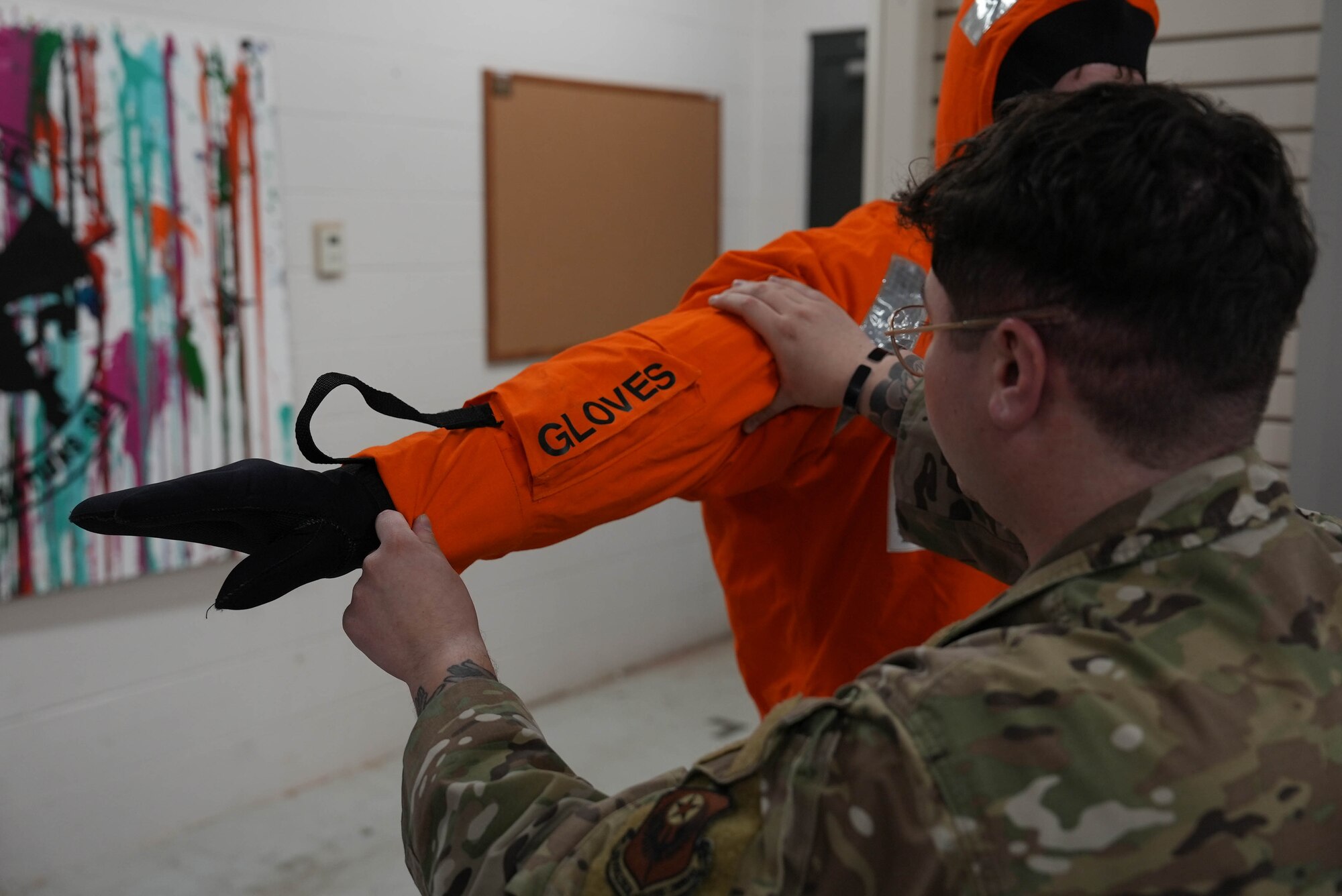 An Air Commando dons a Viking Suit with the help of an aircrew flight equipment specialist at Cannon Air Force Base, New Mexico, March 17, 2025. The suit is designed to improve the survivability of aircrew members in the case of egress in maritime environments, enabling U-28A Draco crews to be ready for any environment. (U.S. Air Force photo by Staff Sgt. Kevin Williams)