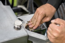 The hand of a Soldier is seen as he polishes the silver portion of a modified 3-inch M5 anti-tank gun for the Presidential Salute Battery