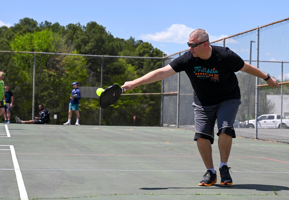 A person hits a pickleball at a tennis court