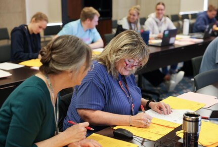 Carderock employees Maureen Foley (right) and Melanie Zajic (left) from the Platform Integrity Department, volunteer to help score students’ written examinations from the individual sprint and team rounds during the Carderock Math Contest (CMC) on April 4, 2025, in West Bethesda, Md.